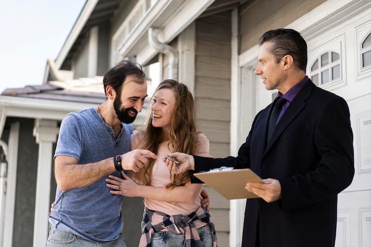 Couple receiving house keys from estate agent outside their new home